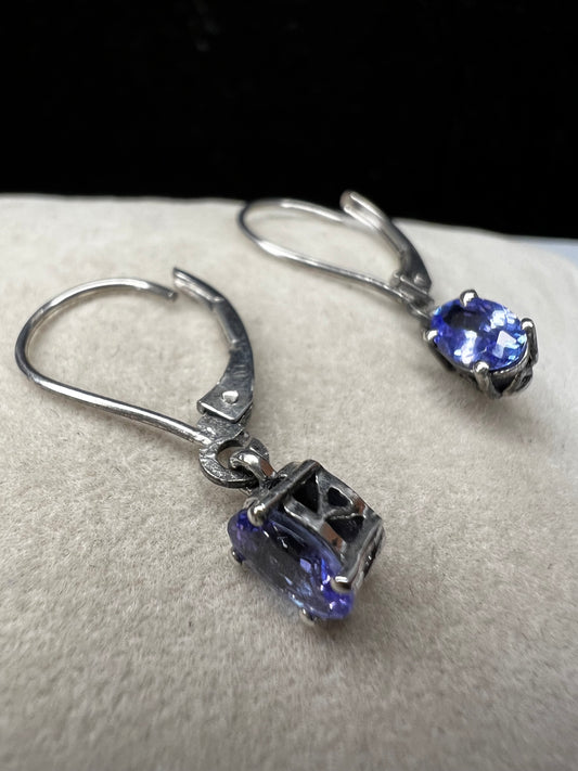 These sterling silver drop earrings feature a delicate tanzanite gemstone, adding a subtle splash of color and graceful movement to your look. Ideal for everyday wear or special occasions.
