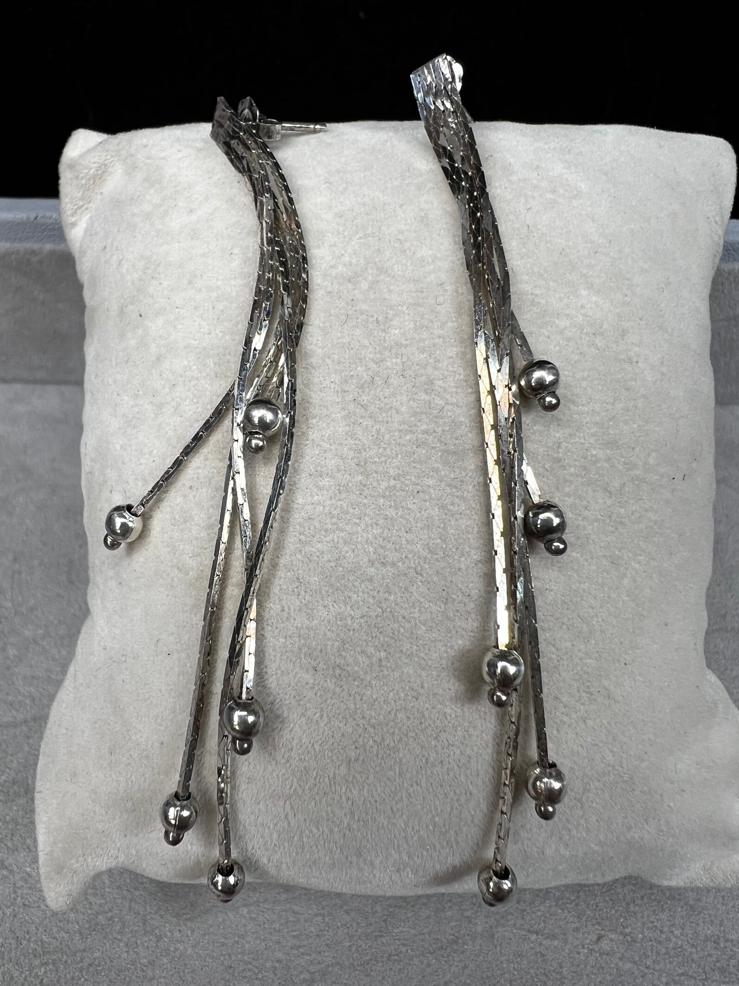 These sterling silver dangle earrings feature five chains of varying lengths, each adorned with a slide bead that moves gracefully with you. Their dynamic design adds elegant motion to your look, making them a charming accessory for any occasion.