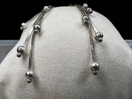 These sterling silver dangle earrings feature five chains of varying lengths, each adorned with a slide bead that moves gracefully with you. Their dynamic design adds elegant motion to your look, making them a charming accessory for any occasion.