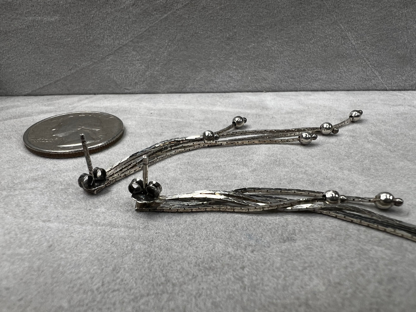 These sterling silver dangle earrings feature five chains of varying lengths, each adorned with a slide bead that moves gracefully with you. Their dynamic design adds elegant motion to your look, making them a charming accessory for any occasion.