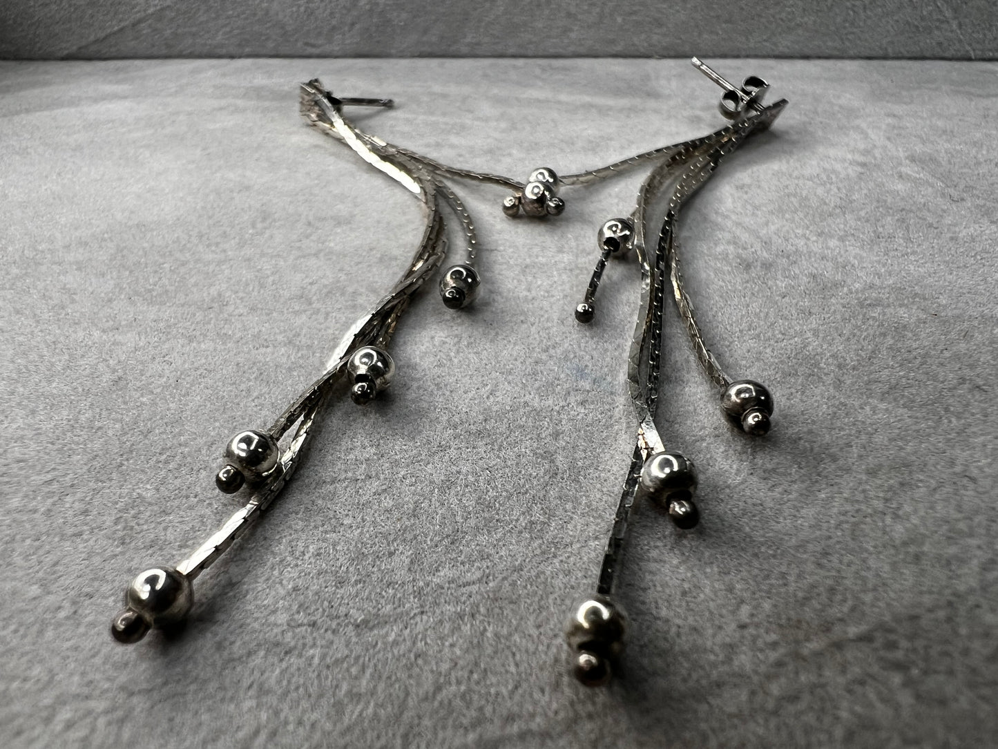 These sterling silver dangle earrings feature five chains of varying lengths, each adorned with a slide bead that moves gracefully with you. Their dynamic design adds elegant motion to your look, making them a charming accessory for any occasion.