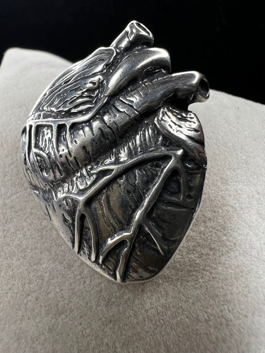 This sterling silver brooch, titled "Collision of Ideas," is expertly crafted to resemble a human heart. Its unique design combines artistic expression with fine craftsmanship.
