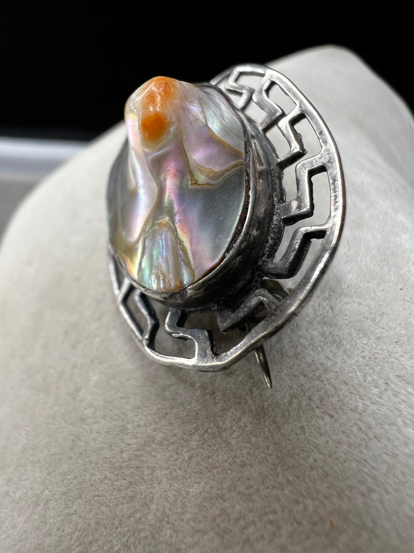 This vintage brooch showcases a tall abalone shell beautifully set within a sterling silver frame that features a classic Greek key design. Its elegant combination of natural iridescence and timeless pattern makes it a standout accessory that adds refined charm to any ensemble.