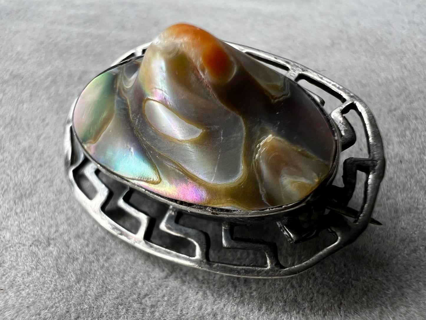 This vintage brooch showcases a tall abalone shell beautifully set within a sterling silver frame that features a classic Greek key design. Its elegant combination of natural iridescence and timeless pattern makes it a standout accessory that adds refined charm to any ensemble.