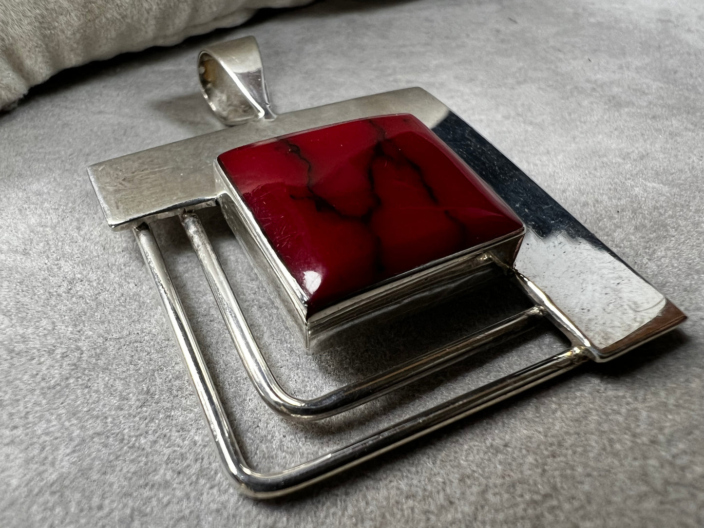 This striking sterling silver pendant features a bold blood red faux stone, designed to stand out beautifully with larger silver chains. Handcrafted in Mexico, it combines unique artistry with timeless elegance, making it a perfect statement piece to complement your collection.