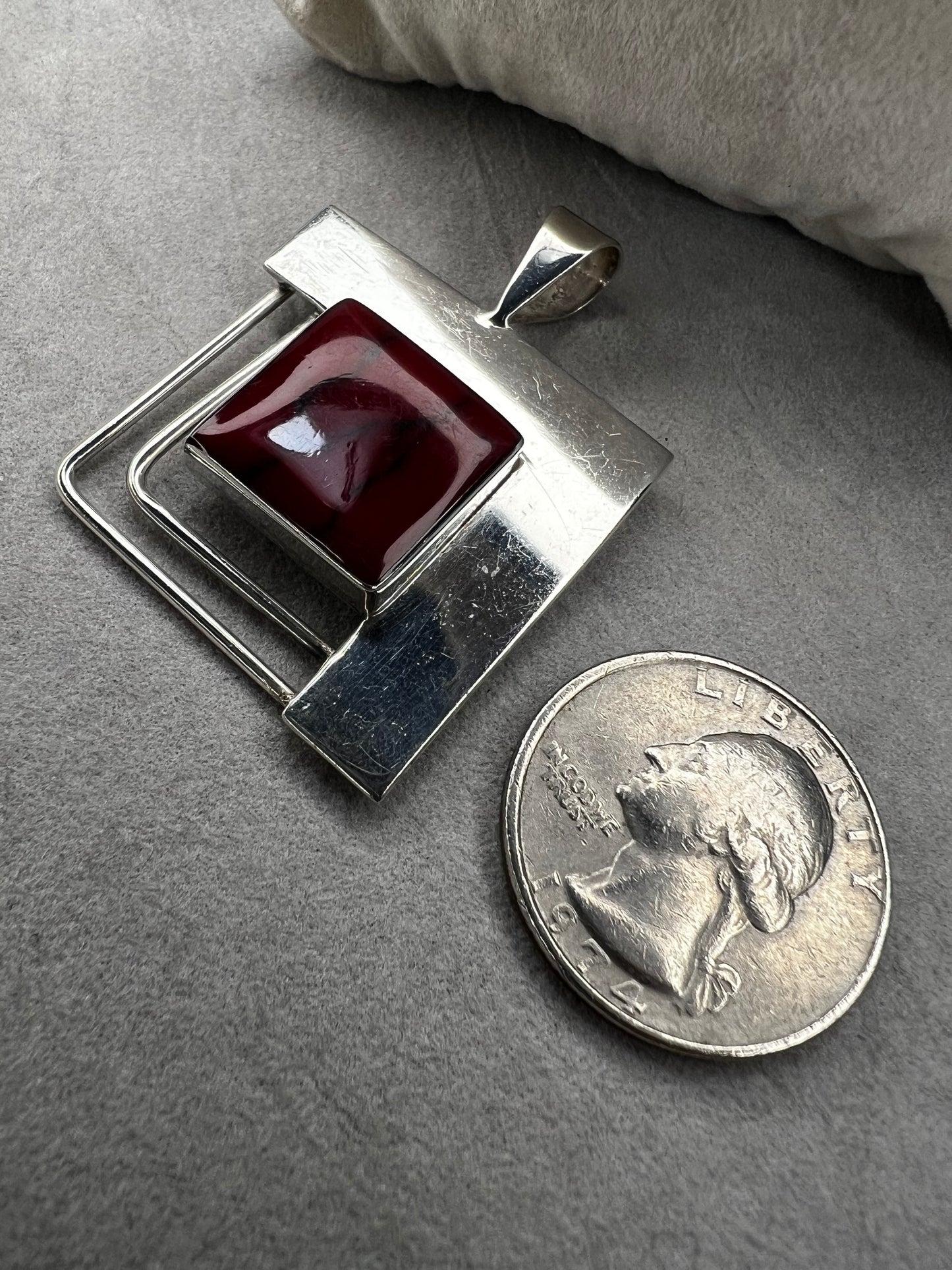 This striking sterling silver pendant features a bold blood red faux stone, designed to stand out beautifully with larger silver chains. Handcrafted in Mexico, it combines unique artistry with timeless elegance, making it a perfect statement piece to complement your collection.