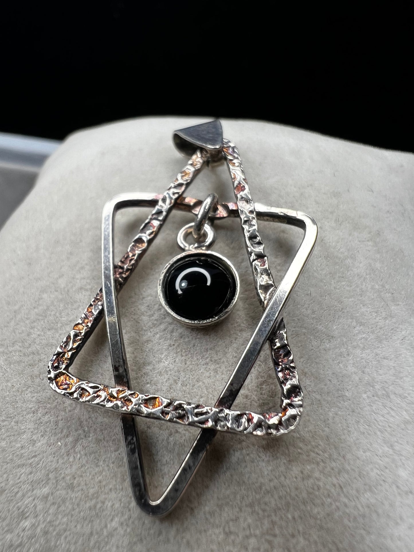 Crafted from sterling silver and marked Israel, this Star of David pendant features a striking jet cabochon delicately suspended in the center. Its thoughtful design combines tradition with elegance, making it a meaningful accessory that supports your personal expression of faith.