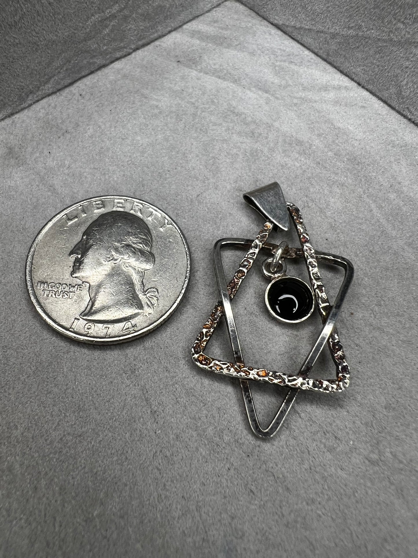 Crafted from sterling silver and marked Israel, this Star of David pendant features a striking jet cabochon delicately suspended in the center. Its thoughtful design combines tradition with elegance, making it a meaningful accessory that supports your personal expression of faith.