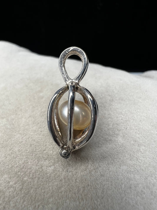 This sterling silver cage pendant features a natural pearl inside and opens up for a unique touch. it can be worn as a pendant or charm, offering a delicate and elegant addition to your jewelry collection. Signed LUC.