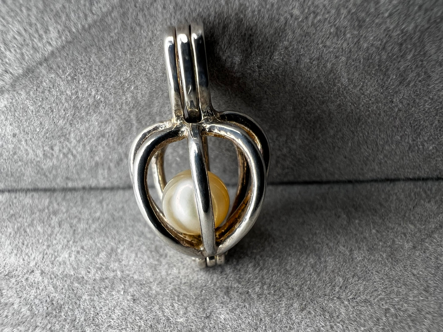 This sterling silver cage pendant features a natural pearl inside and opens up for a unique touch. it can be worn as a pendant or charm, offering a delicate and elegant addition to your jewelry collection. Signed LUC.