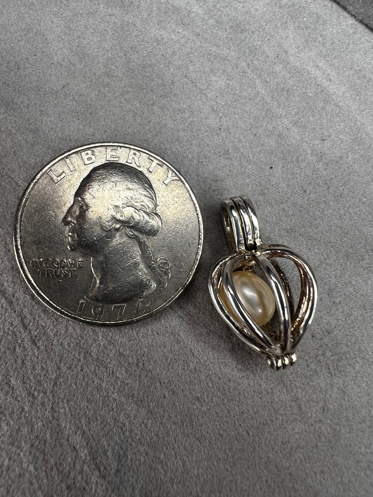 This sterling silver cage pendant features a natural pearl inside and opens up for a unique touch. it can be worn as a pendant or charm, offering a delicate and elegant addition to your jewelry collection. Signed LUC.