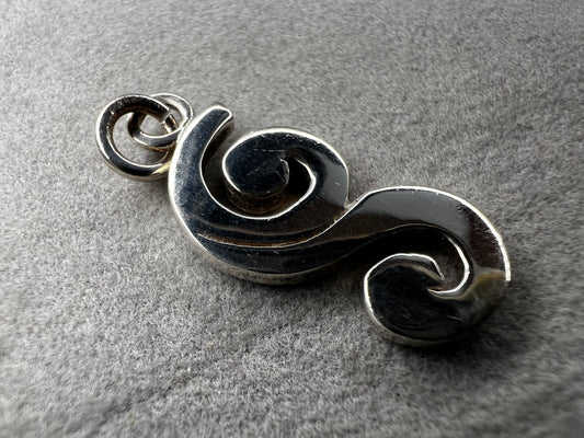 This sterling silver piece offers the flexibility to be worn as a charm or pendant, adapting effortlessly to your style. Signed Barse.