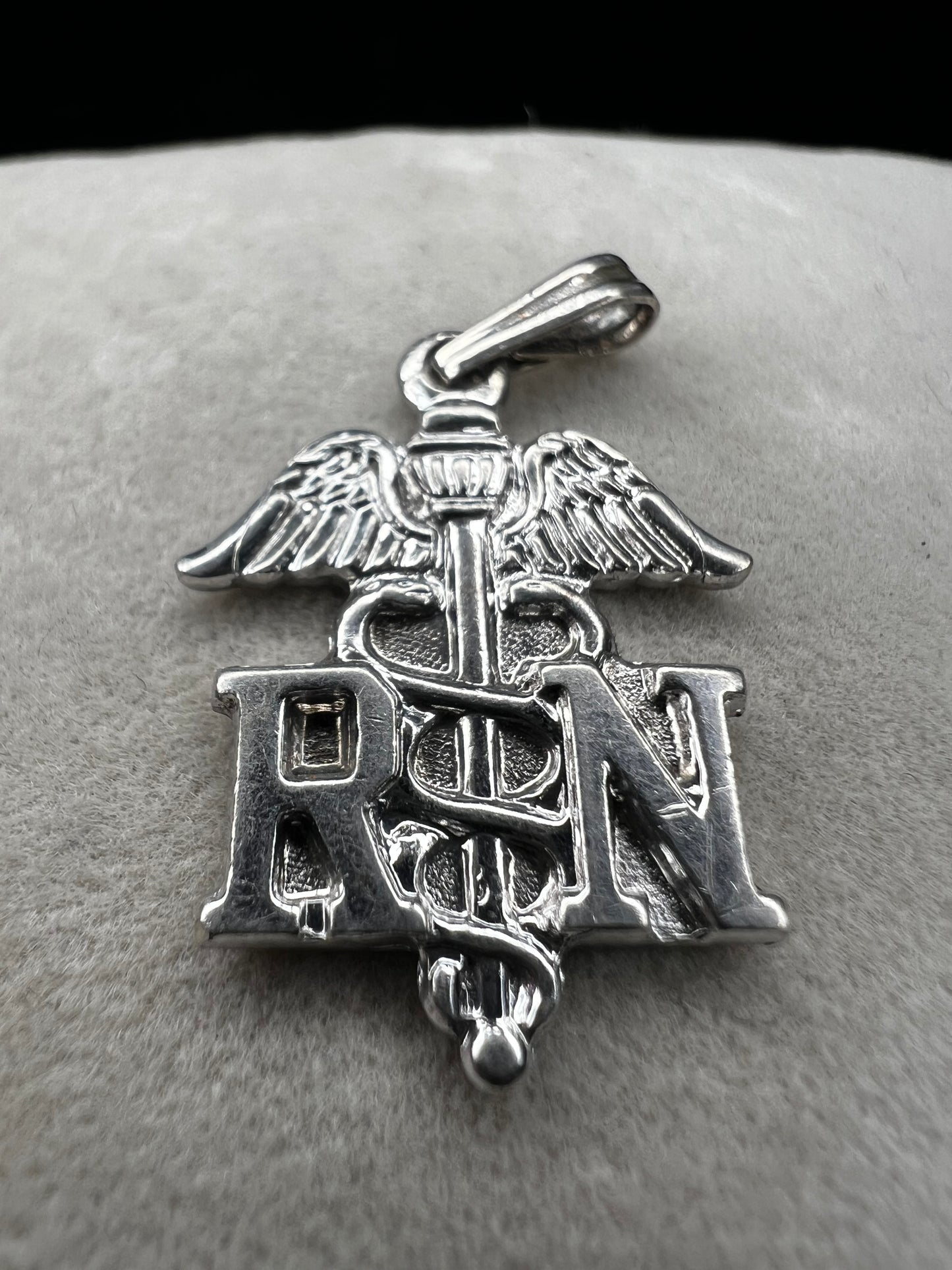 Celebrate the dedication of nurses with this vintage sterling silver RN pendant. It serves as a meaningful symbol of commitment and care. Perfect for everyday wear or as a thoughtful gift.