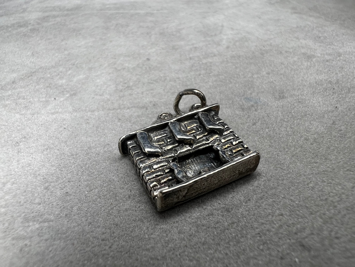 This Danecraft sterling silver charm captures the cozy holiday spirit with stockings hanging from the mantle above a wood-burning fire. It’s a charming addition to your Christmas collection, perfect for celebrating festive traditions and adding warmth to your jewelry.