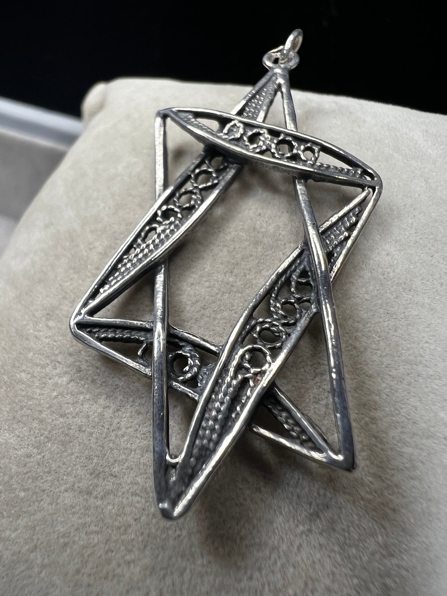 This sterling silver Star of David pendant, measuring nearly 2 inches, showcases intricate filigree craftsmanship. Its delicate design highlights expert artistry, making it a meaningful and elegant accessory.