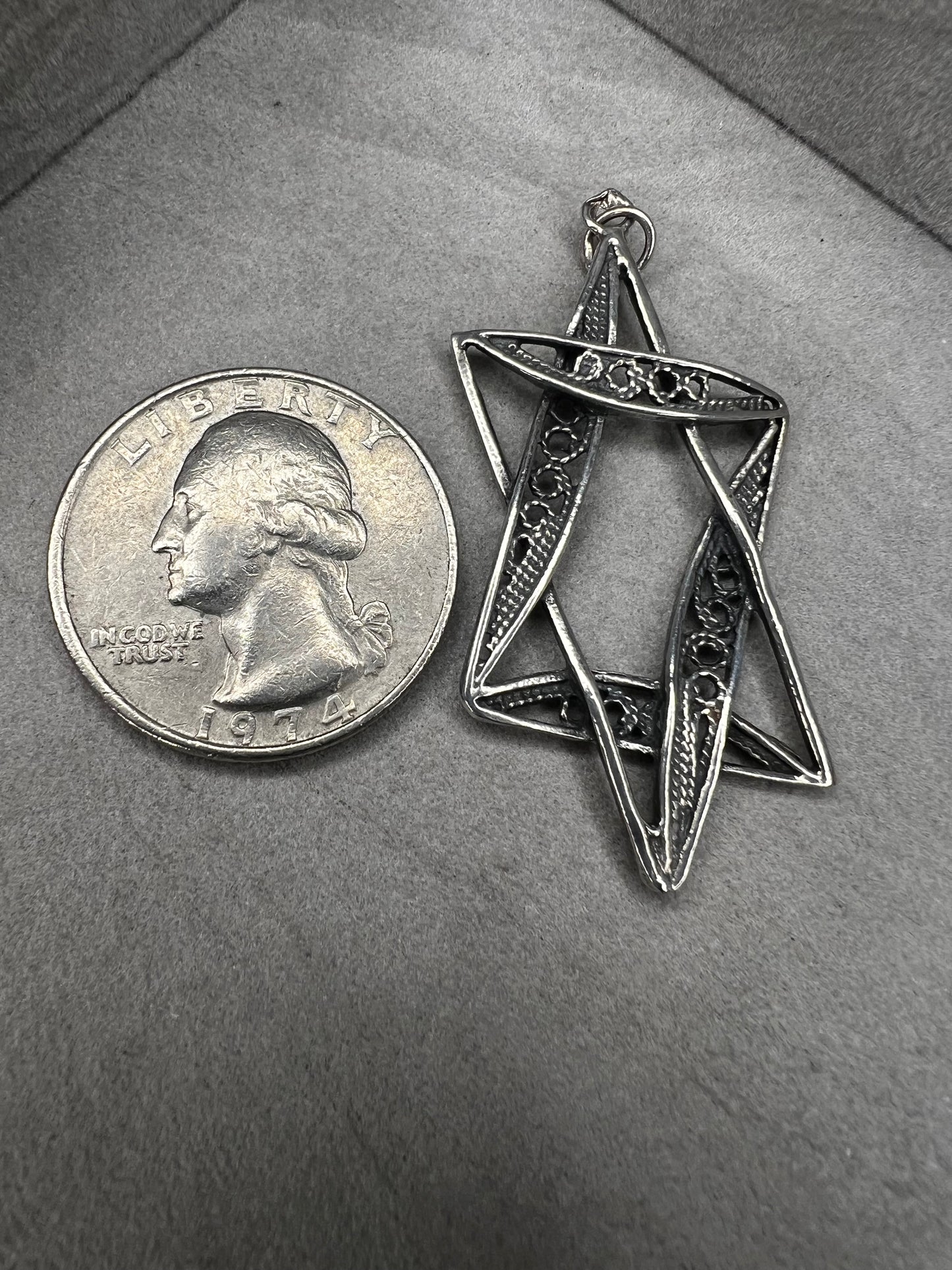 This sterling silver Star of David pendant, measuring nearly 2 inches, showcases intricate filigree craftsmanship. Its delicate design highlights expert artistry, making it a meaningful and elegant accessory.