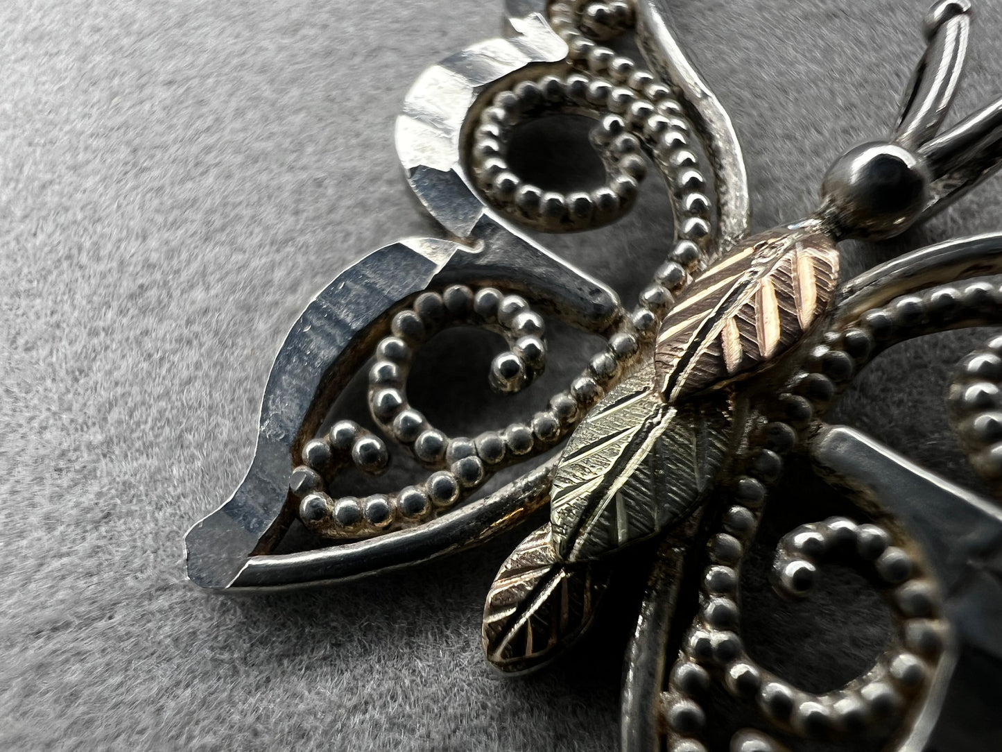 This vintage butterfly pendant combines the timeless elegance of sterling silver with the rich warmth of 12 karat gold. Signed C. Co., this Black Hills Gold piece is perfect for those who appreciate classic craftsmanship with a touch of sophistication.
