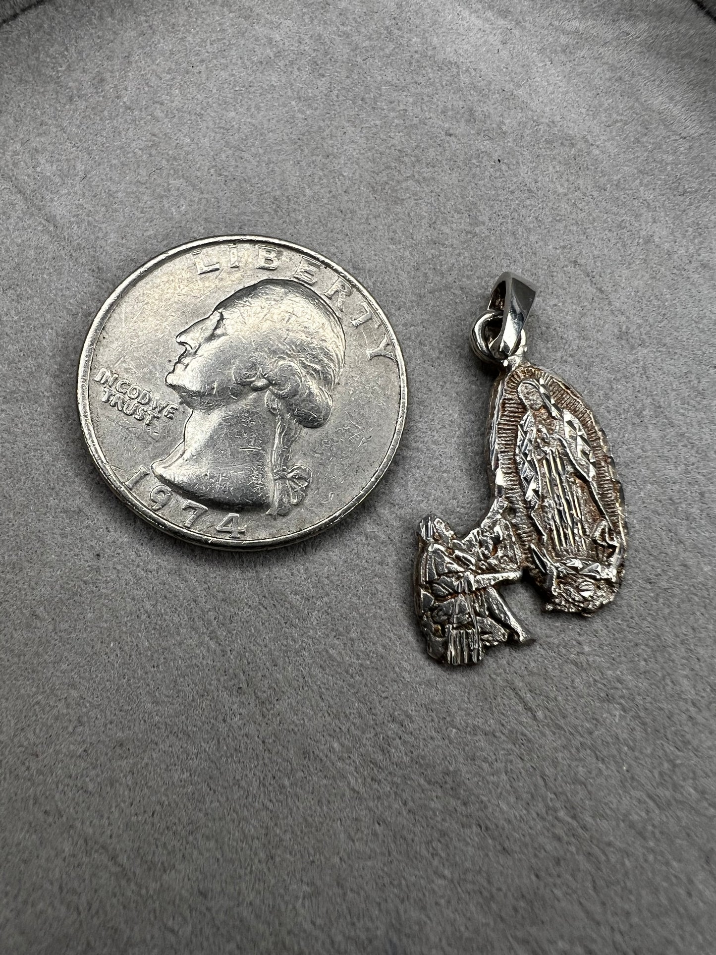 Crafted from sterling silver, this pendant shows a figure kneeling before another, suggestive of a religious deity. This piece is detailed with diamond cuts to catch the light.