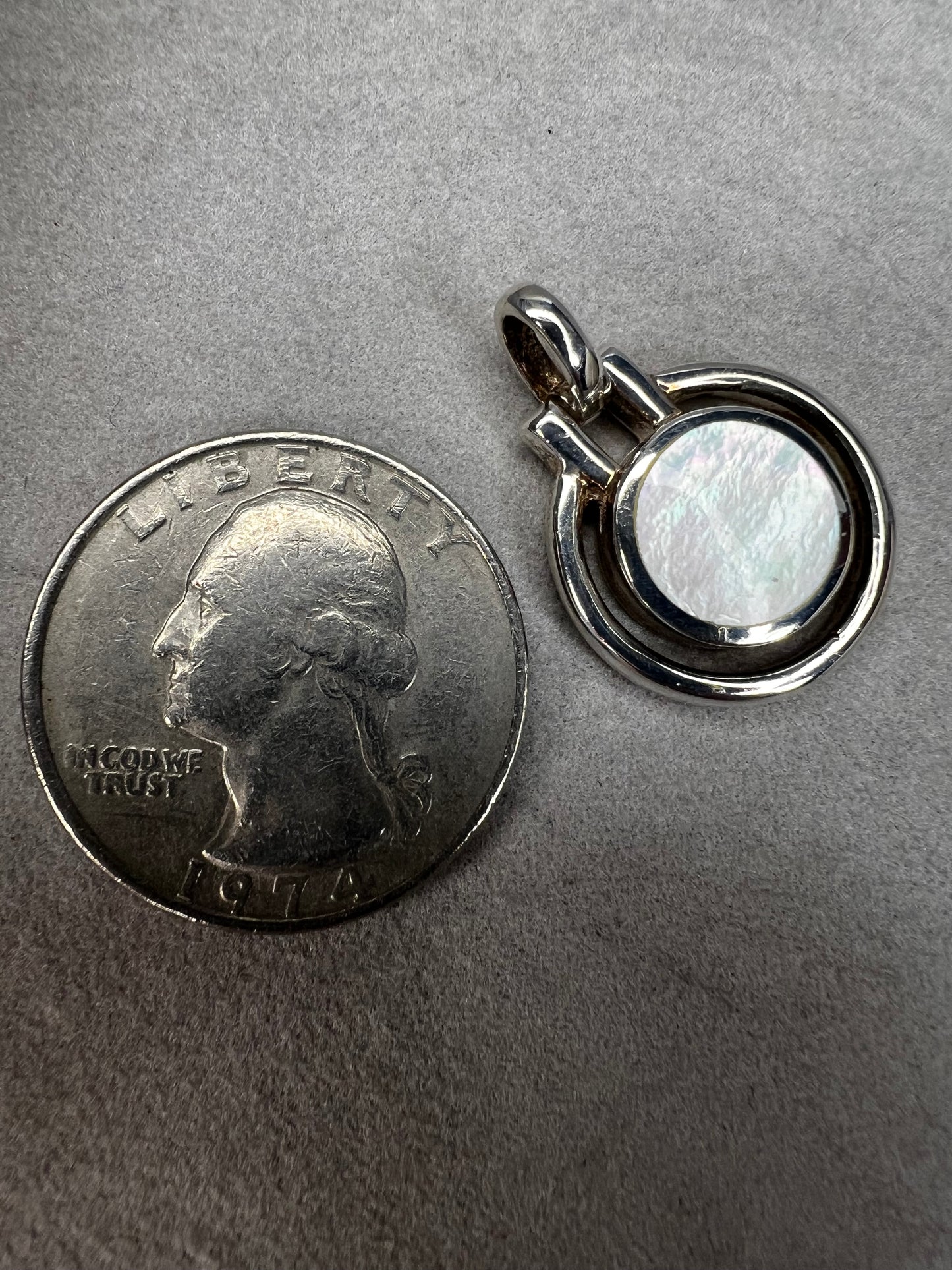 This sterling silver and mother of pearl pendant features a seamless design where the outer ring and bail are crafted as a single unit. The circular shape highlights the natural iridescence of the mother of pearl.