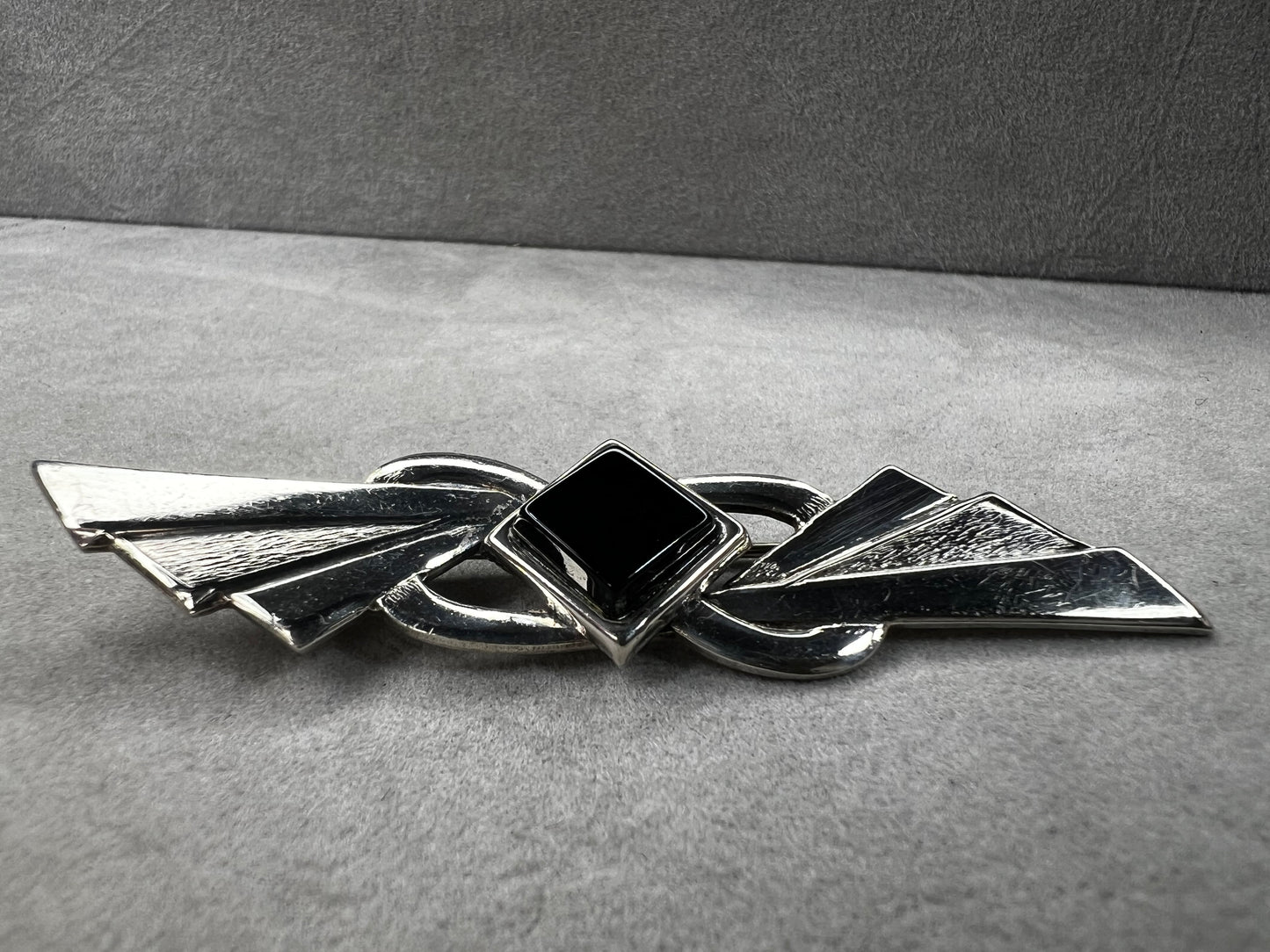 This vintage brooch is crafted from 800 silver and features a striking black diamond-shaped Jet centerpiece. Its classic design adds a sophisticated vintage touch to any outfit.