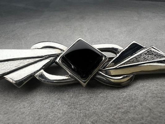This vintage brooch is crafted from 800 silver and features a striking black diamond-shaped Jet centerpiece. Its classic design adds a sophisticated vintage touch to any outfit.
