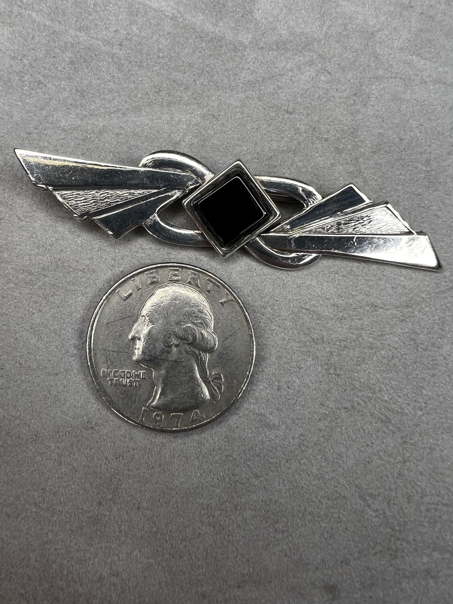 This vintage brooch is crafted from 800 silver and features a striking black diamond-shaped Jet centerpiece. Its classic design adds a sophisticated vintage touch to any outfit.