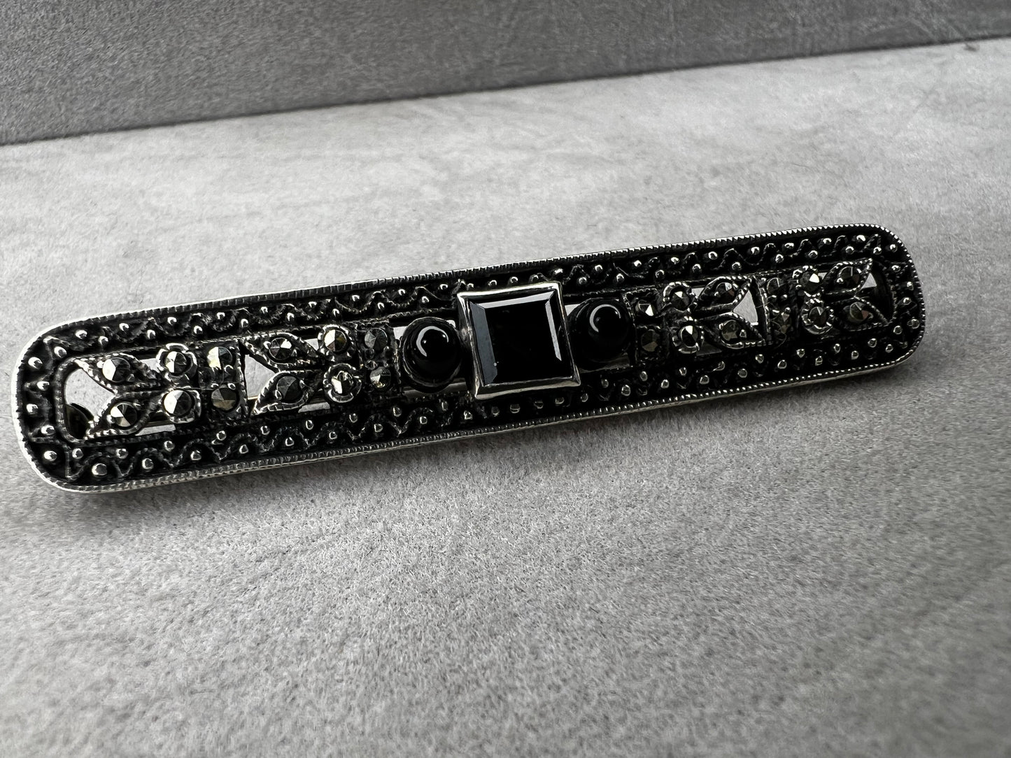 This exquisite 2-inch sterling silver bar brooch features authentic marcasite and jet stones, embodying the timeless elegance of the Art Deco era. It's a distinctive accessory that complements both vintage and modern styles.