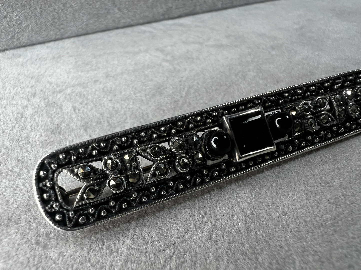 This exquisite 2-inch sterling silver bar brooch features authentic marcasite and jet stones, embodying the timeless elegance of the Art Deco era. It's a distinctive accessory that complements both vintage and modern styles.