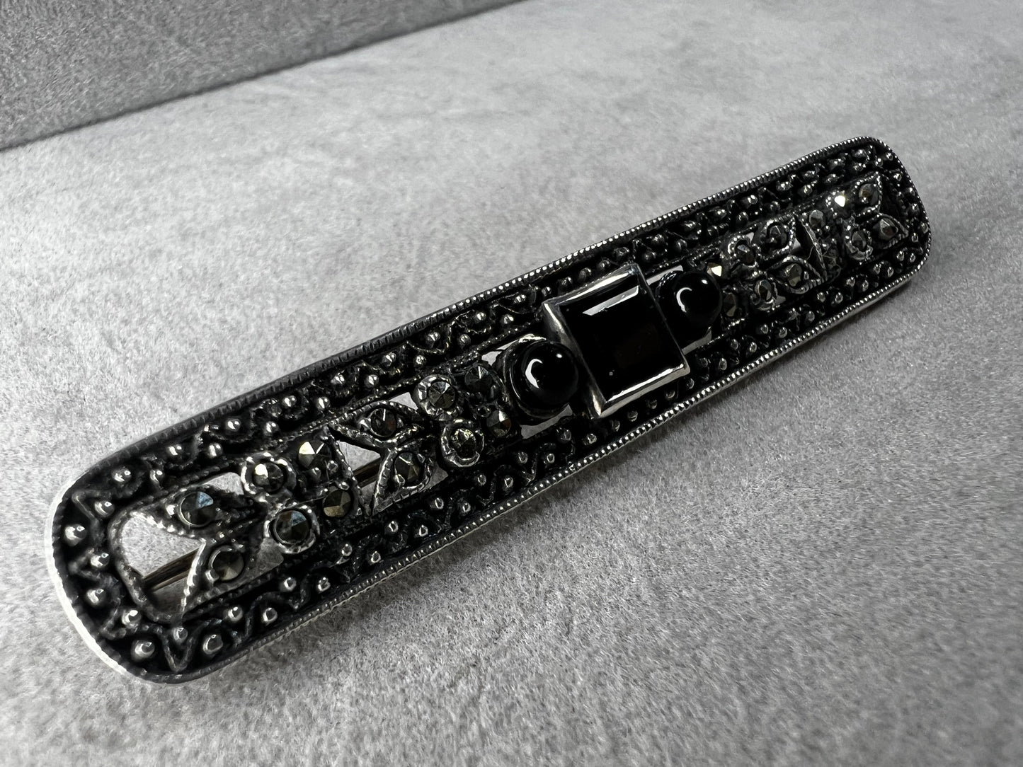This exquisite 2-inch sterling silver bar brooch features authentic marcasite and jet stones, embodying the timeless elegance of the Art Deco era. It's a distinctive accessory that complements both vintage and modern styles.