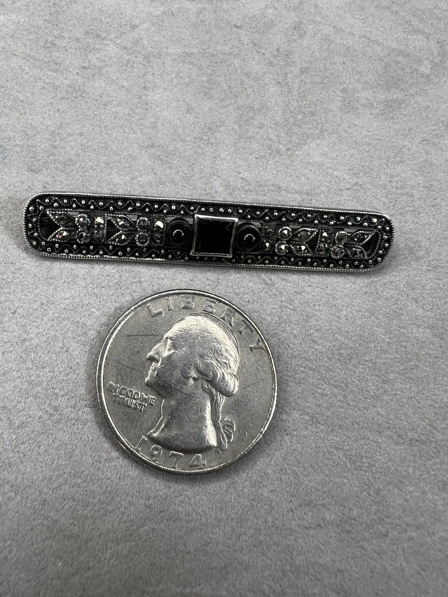 This exquisite 2-inch sterling silver bar brooch features authentic marcasite and jet stones, embodying the timeless elegance of the Art Deco era. It's a distinctive accessory that complements both vintage and modern styles.