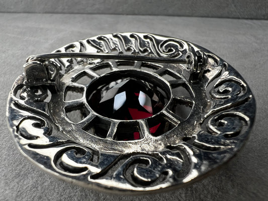 This vintage sterling silver brooch measures 1.5" in diameter and features an elegant open work design. The marcasites catch the light beautifully, while the deep purple faux stone adds a rich, eye-catching touch. Perfect for adding timeless charm to any outfit.