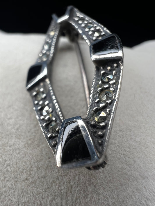 This vintage mid-century brooch combines sterling silver, marcasite, and enamel to create a timeless accessory. Its classic design adds a touch of elegance and history to any jewelry collection.