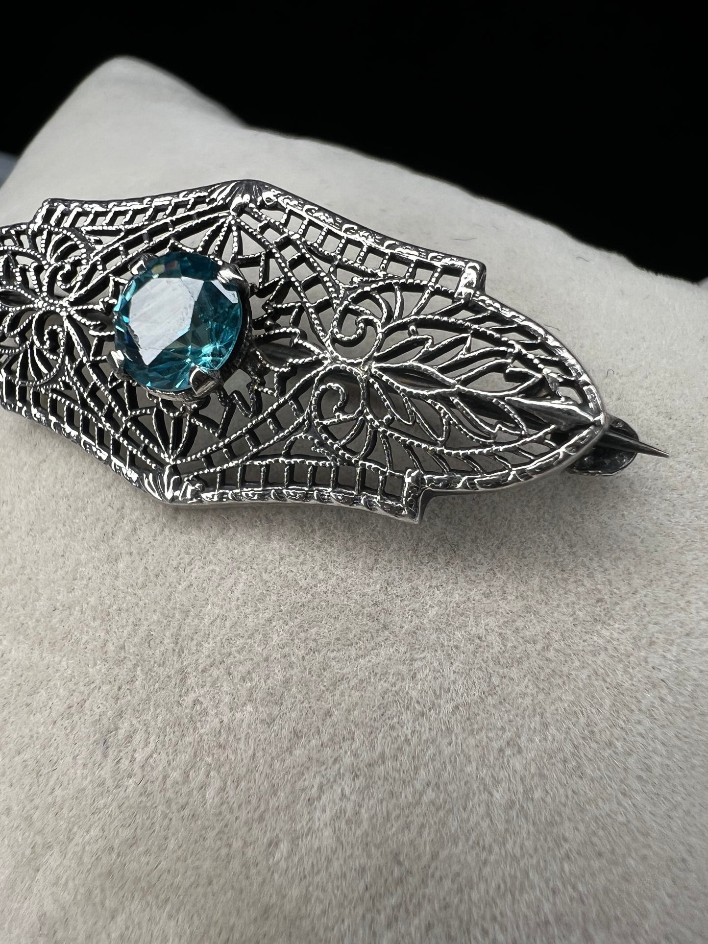 This antique filigree brooch features a beautiful blue topaz set in sterling silver, signed with a distinctive "K." Measuring 1.5 inches, it offers a delicate and elegant touch to any jewelry collection. Perfect for adding a vintage charm to your style.