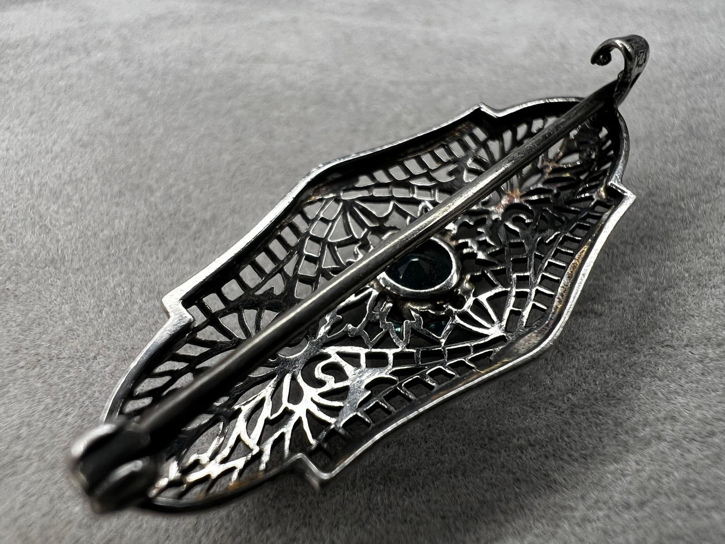 This antique filigree brooch features a beautiful blue topaz set in sterling silver, signed with a distinctive "K." Measuring 1.5 inches, it offers a delicate and elegant touch to any jewelry collection. Perfect for adding a vintage charm to your style.