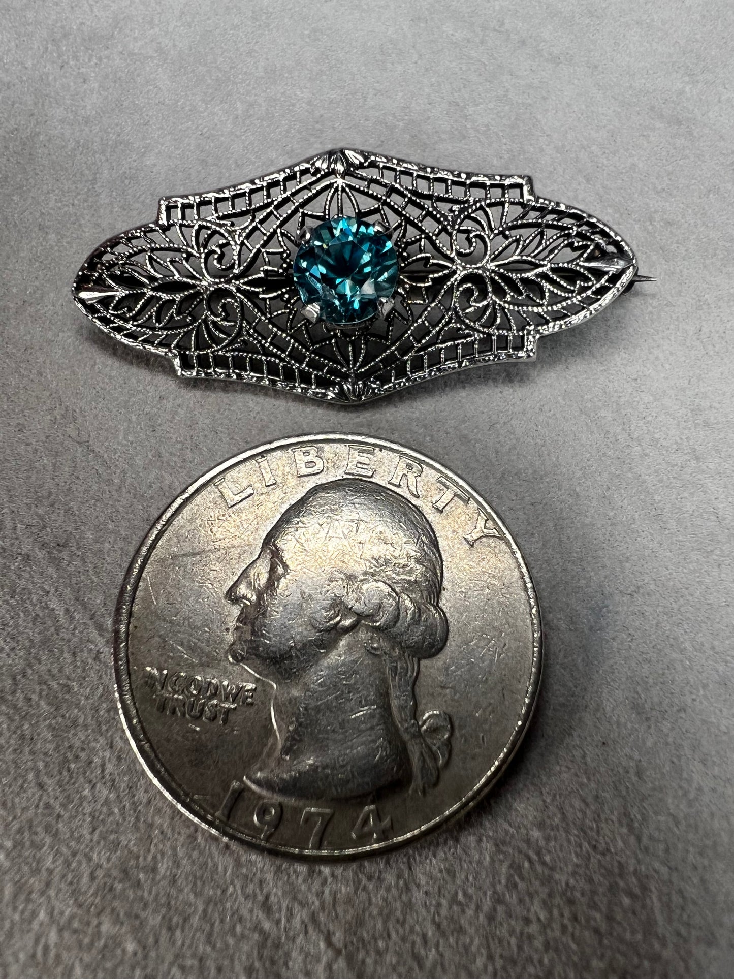 This antique filigree brooch features a beautiful blue topaz set in sterling silver, signed with a distinctive "K." Measuring 1.5 inches, it offers a delicate and elegant touch to any jewelry collection. Perfect for adding a vintage charm to your style.