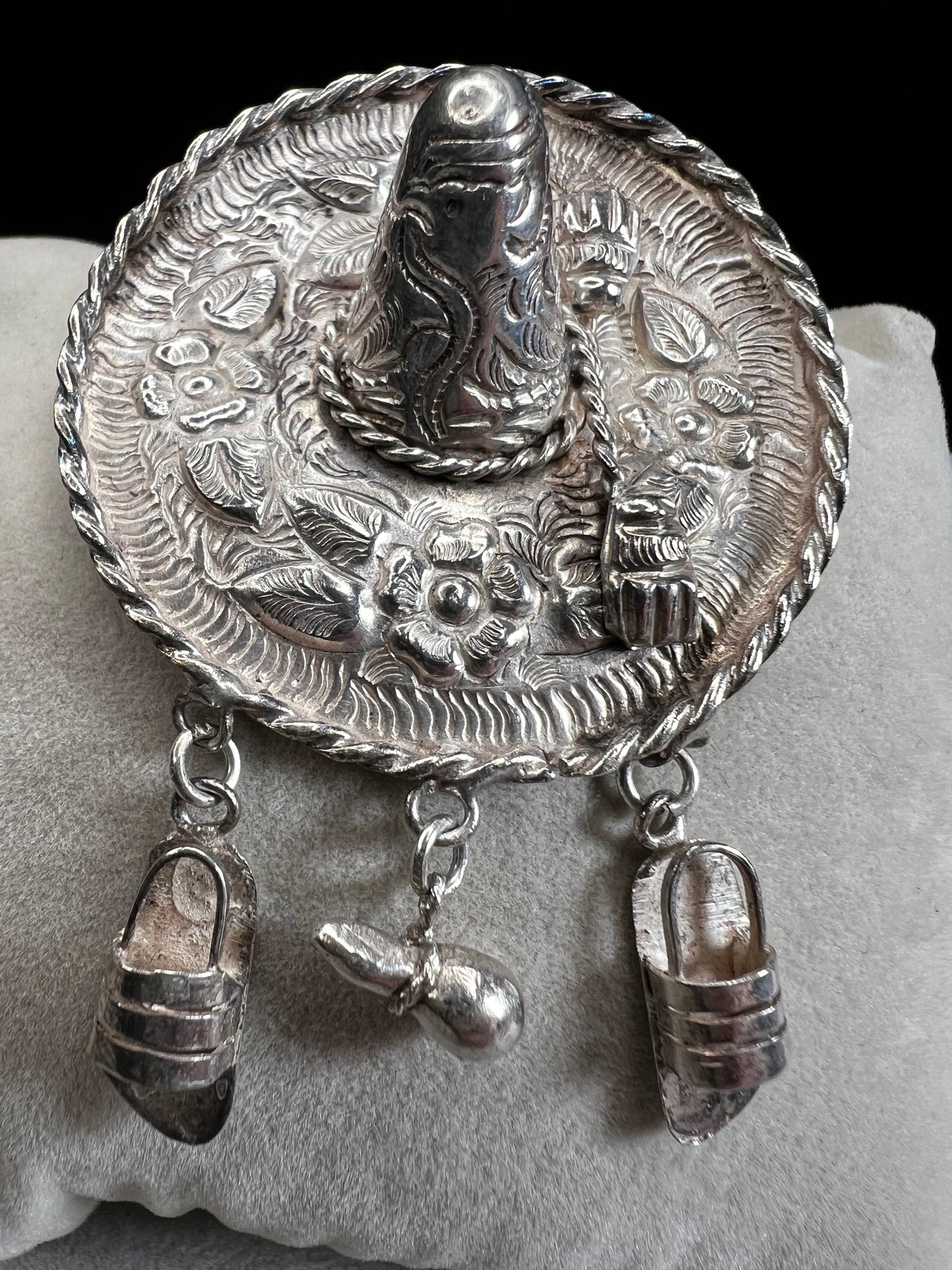 This charming 1950s sterling silver brooch captures a playful scene with a large sombrero, a pair of sandals, and a maraca. Its unique design reflects vintage character and cultural flair, making it a delightful accessory that adds personality and nostalgia to your collection.