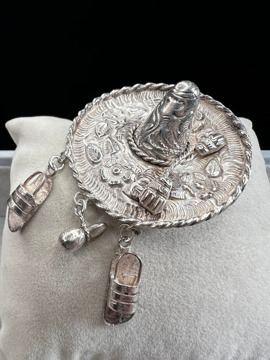 This charming 1950s sterling silver brooch captures a playful scene with a large sombrero, a pair of sandals, and a maraca. Its unique design reflects vintage character and cultural flair, making it a delightful accessory that adds personality and nostalgia to your collection.