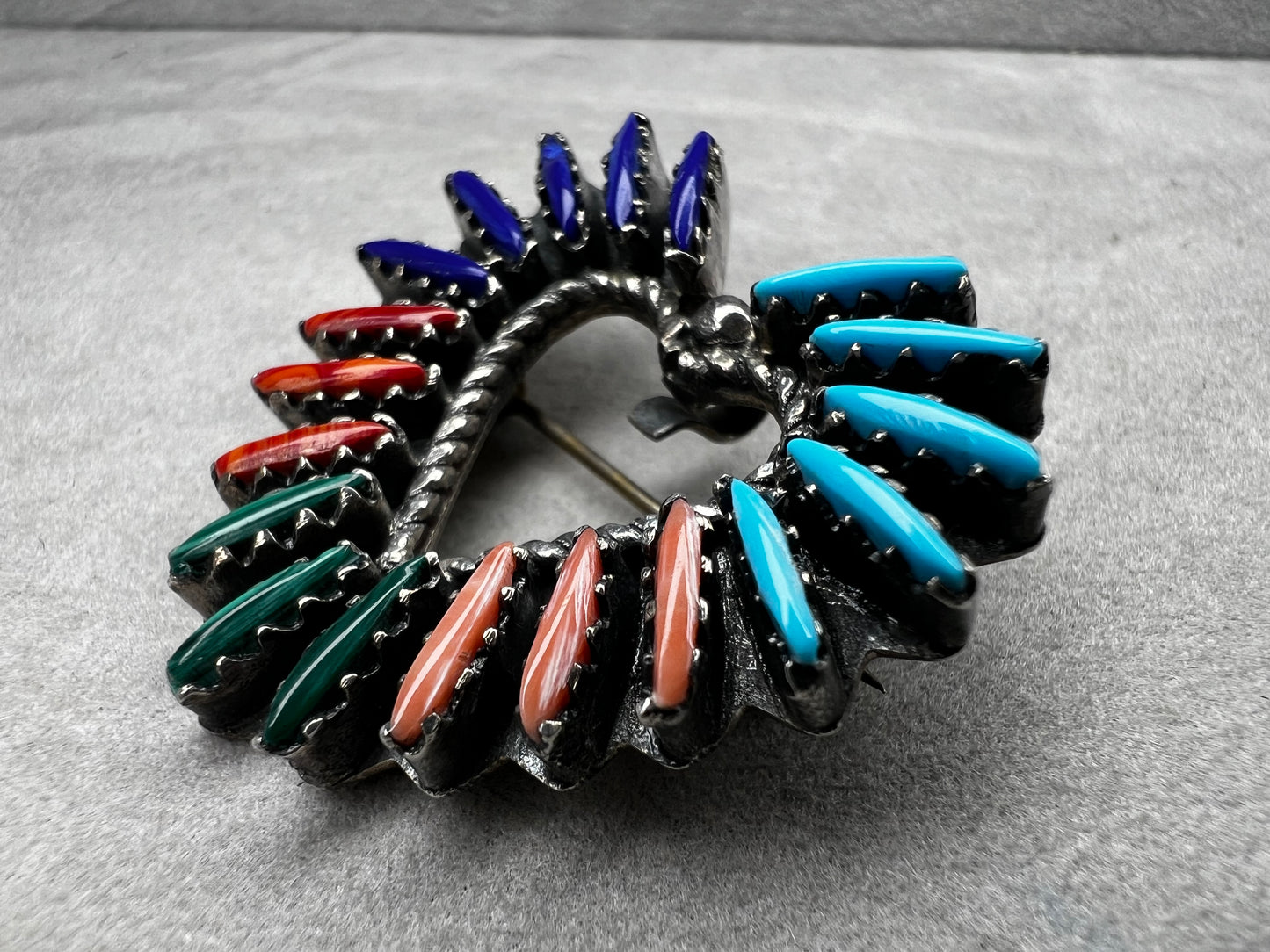 At just over an 1", this is a beautiful vintage Navajo pin done by Tom Taylor, meticulously crafted from sterling silver and natural stones. This is a special piece. There are small chips in some of the stones, but they don't take away from the pin's beauty.
