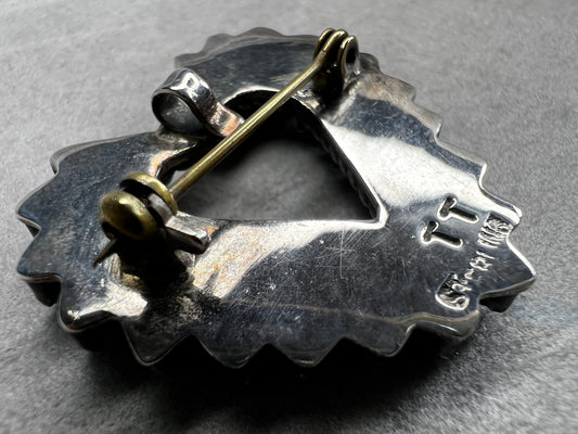 At just over an 1", this is a beautiful vintage Navajo pin done by Tom Taylor, meticulously crafted from sterling silver and natural stones. This is a special piece. There are small chips in some of the stones, but they don't take away from the pin's beauty.