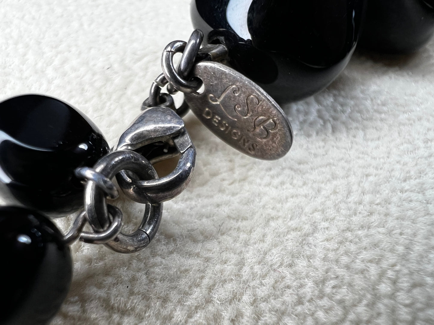 This necklace from LSB Designs features natural black onyx beads and sterling silver, combining striking beauty with lasting durability. Designed to impress, it offers a bold yet elegant accessory that enhances any look.