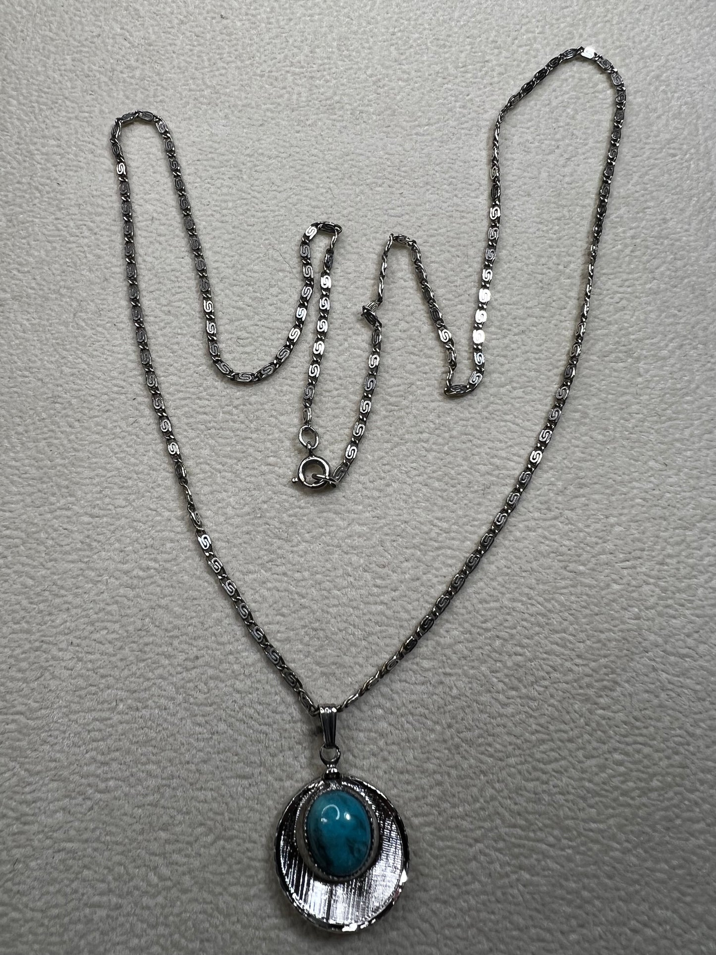 This 20" sterling silver scroll link chain paired with a faux turquoise pendant offers a timeless vintage style.