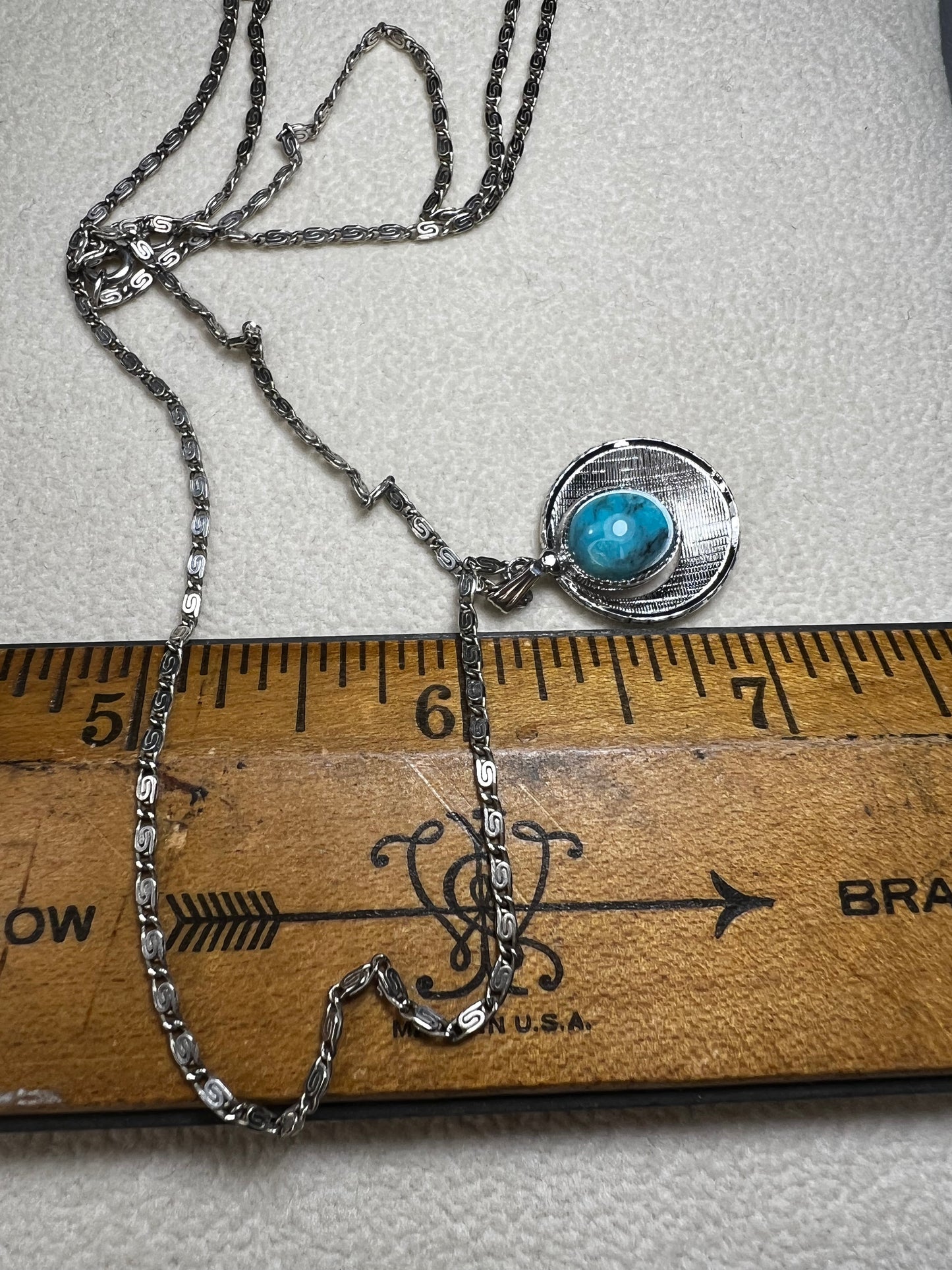 This 20" sterling silver scroll link chain paired with a faux turquoise pendant offers a timeless vintage style.