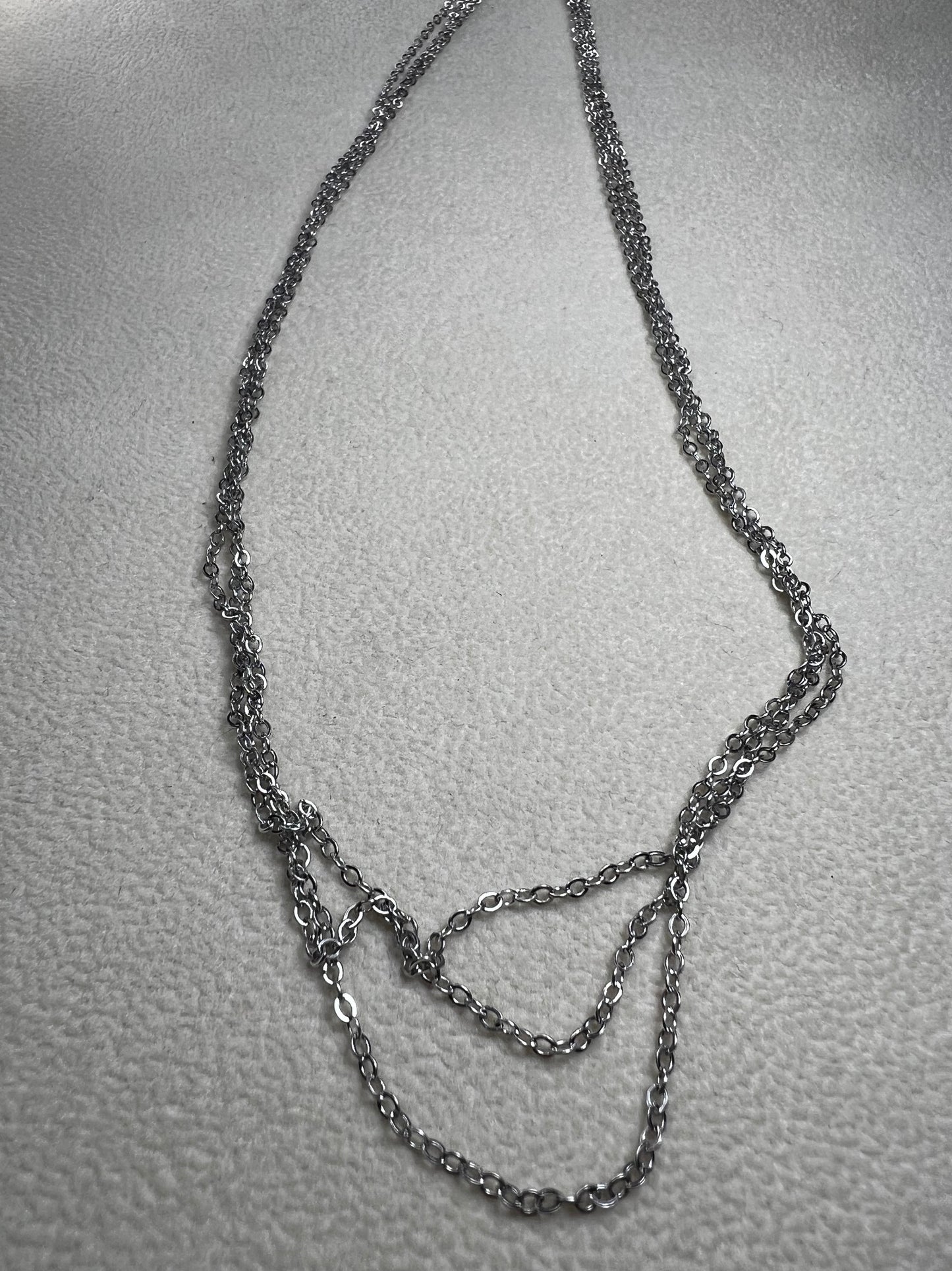 This sterling silver multi-chain necklace features three delicate chains linked together, offering subtle movement and a graceful, layered look. Its versatile design adds a touch of elegance to any outfit.