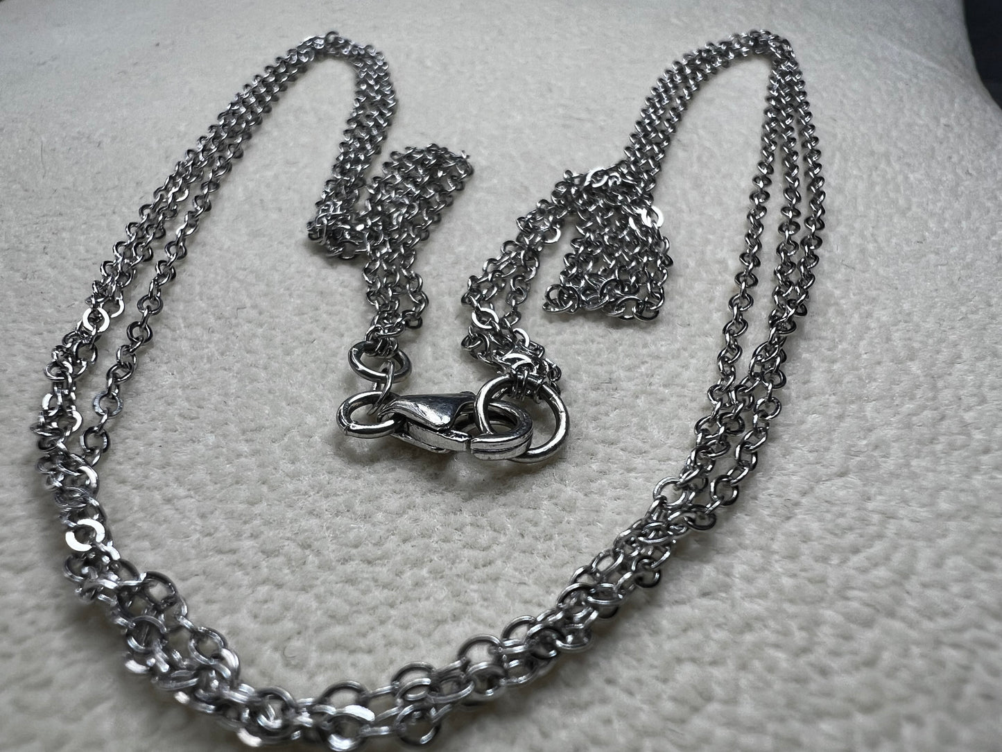 This sterling silver multi-chain necklace features three delicate chains linked together, offering subtle movement and a graceful, layered look. Its versatile design adds a touch of elegance to any outfit.