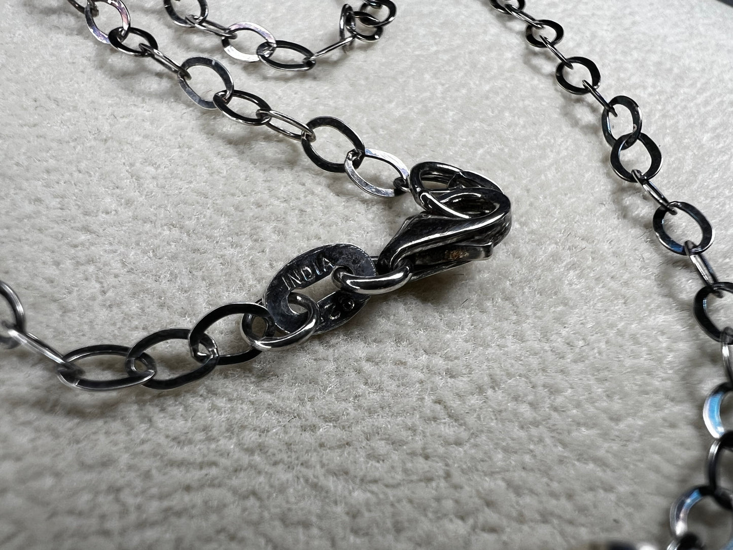 This striking pendant on a chain necklace features a polished Larvikite cabochon, showcasing its distinctive dark gray body with shimmering silver flashes. The stone is set in an artistic sterling silver wirework design, creating a bold and modern statement piece.
