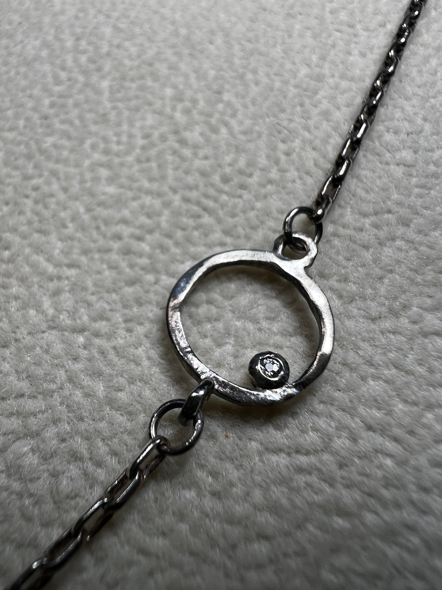 This retired Silpada necklace, measuring 34" in length, is crafted from sterling silver and accented with a few sparkling cubic zirconia stones. This "Ring Around the Rosy" necklace offers a subtle flash of light, making it a charming and elegant addition to any jewelry collection.