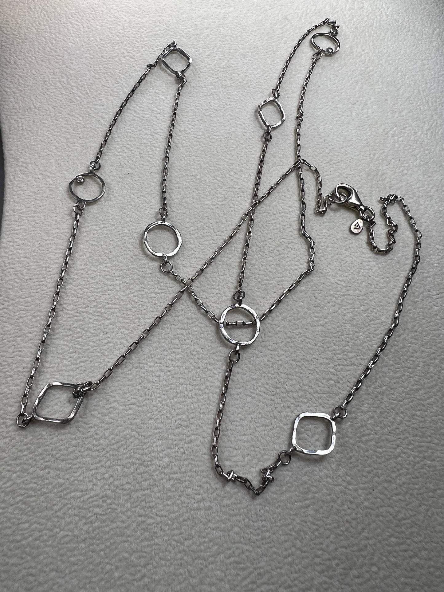 This retired Silpada necklace, measuring 34" in length, is crafted from sterling silver and accented with a few sparkling cubic zirconia stones. This "Ring Around the Rosy" necklace offers a subtle flash of light, making it a charming and elegant addition to any jewelry collection.