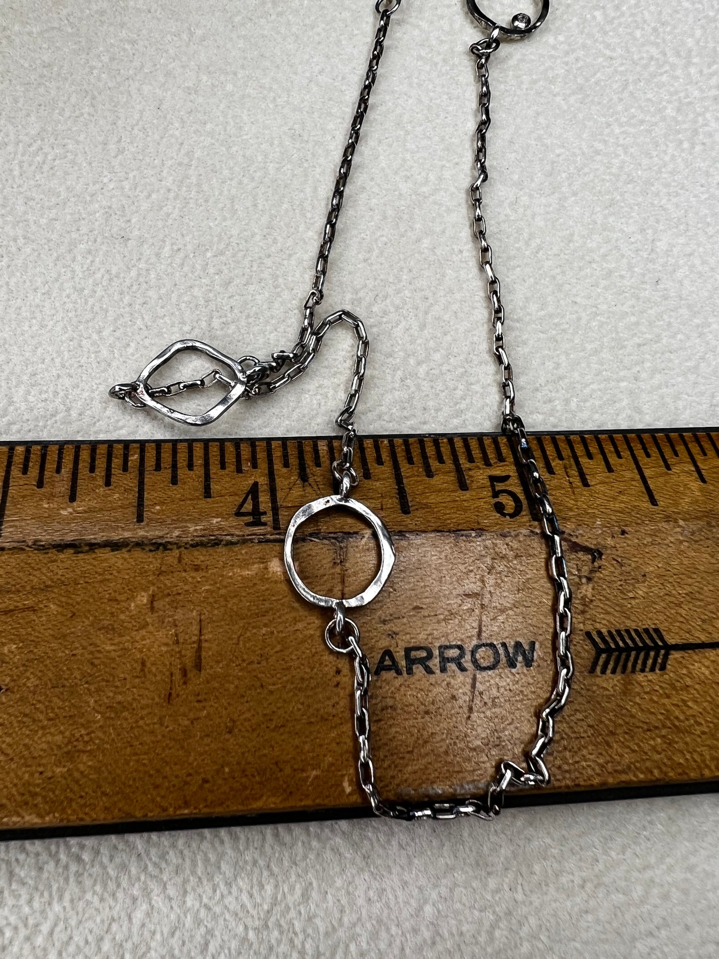 This retired Silpada necklace, measuring 34" in length, is crafted from sterling silver and accented with a few sparkling cubic zirconia stones. This "Ring Around the Rosy" necklace offers a subtle flash of light, making it a charming and elegant addition to any jewelry collection.