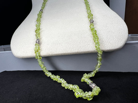 This 36-inch necklace features natural peridot chips expertly strung and paired with sterling silver components. Its vibrant green hues bring a refreshing touch, while sterling silver ensures durability and elegance. Made in India.