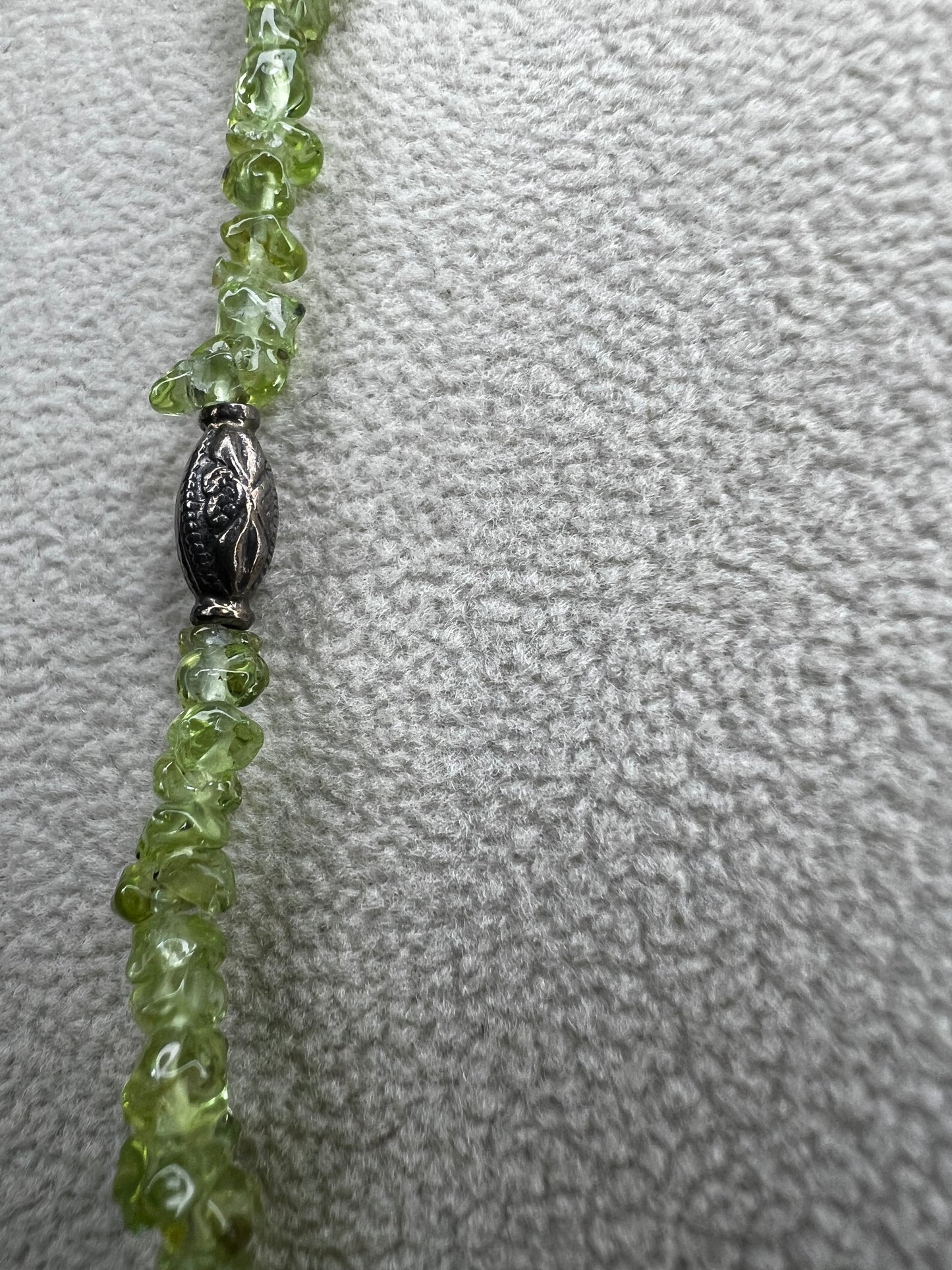 This 36-inch necklace features natural peridot chips expertly strung and paired with sterling silver components. Its vibrant green hues bring a refreshing touch, while sterling silver ensures durability and elegance. Made in India.